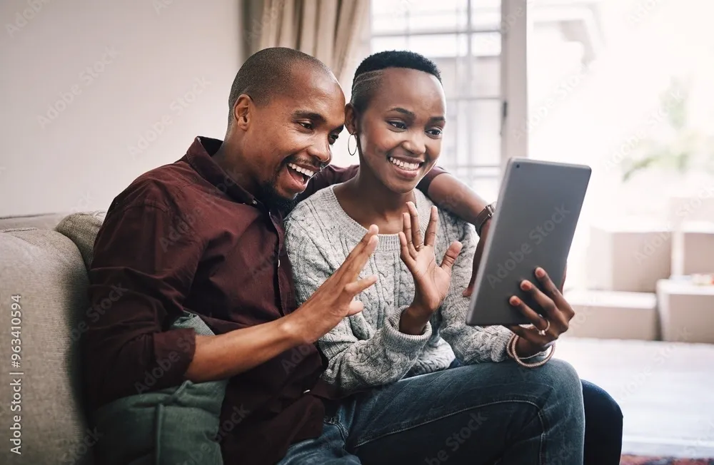 Couple video calling on a tablet, smiling.