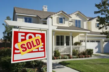 House with "Sold" sign in front yard.