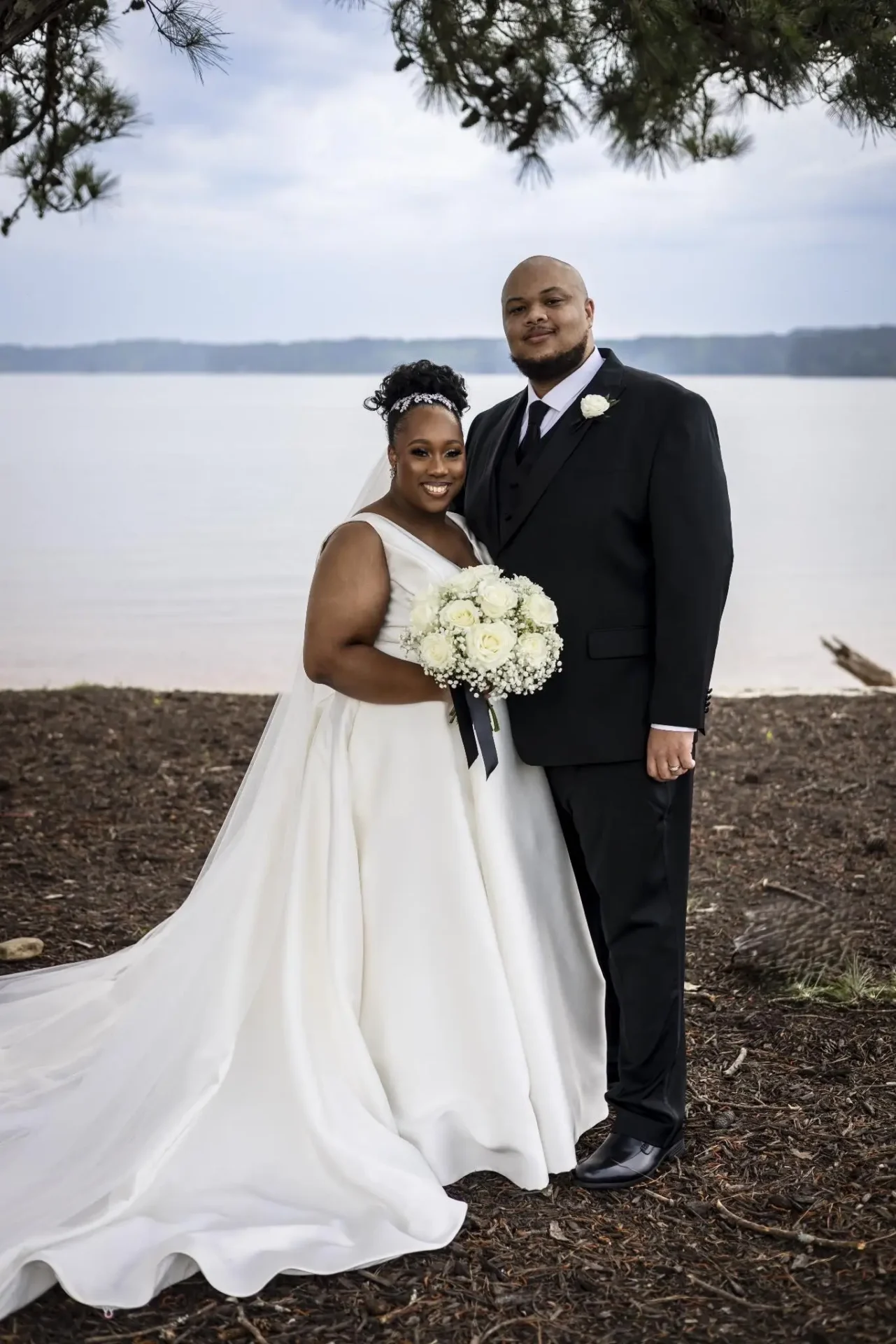 Newlywed couple posing together by the water